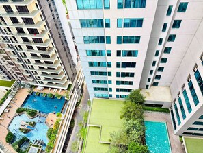 A high-rise building with multiple balconies, a rooftop pool, and a green lawn area. - Mercu summer suites by premium charter  (Kuala Lumpur)