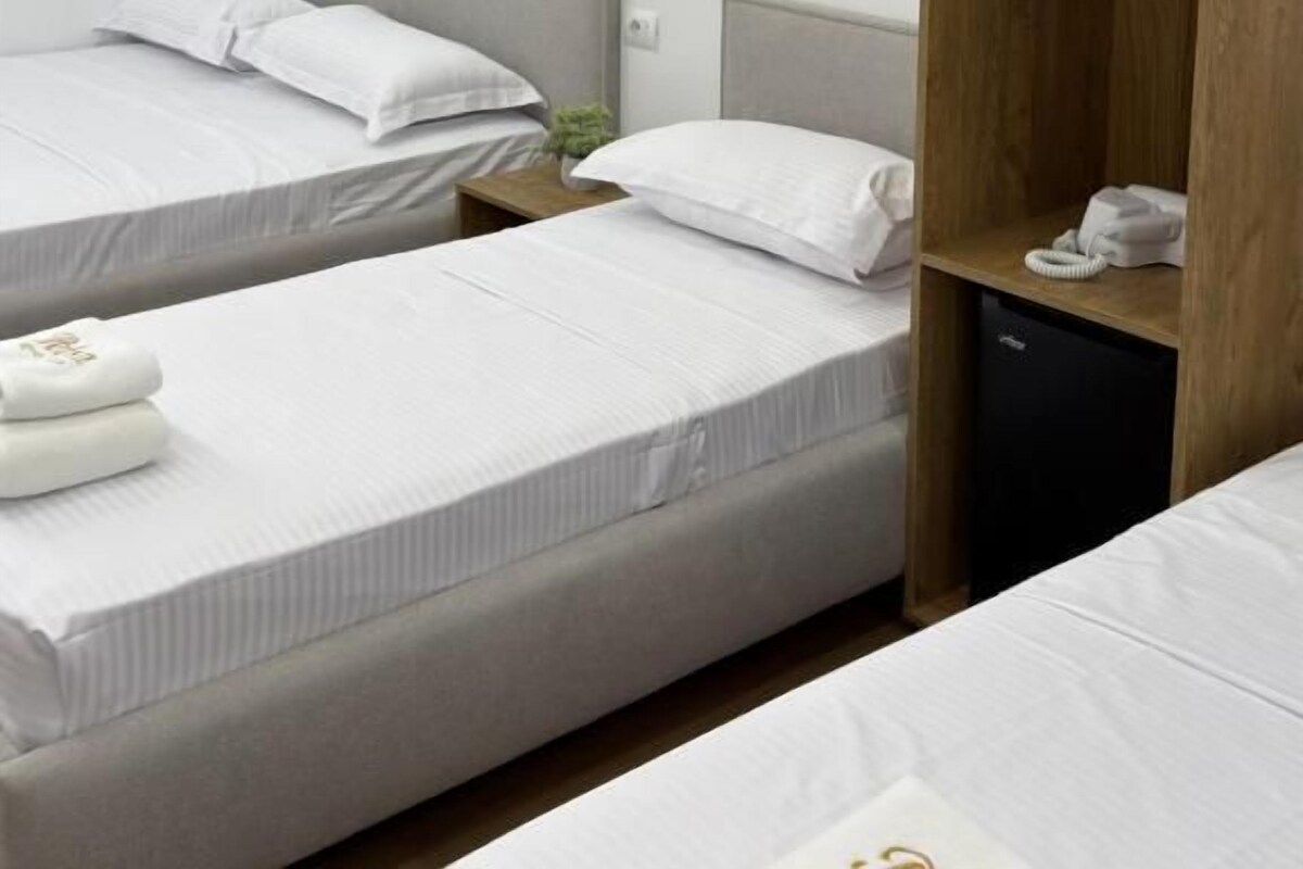 A hotel room with two single beds, a wooden wardrobe, and a small desk with a telephone.