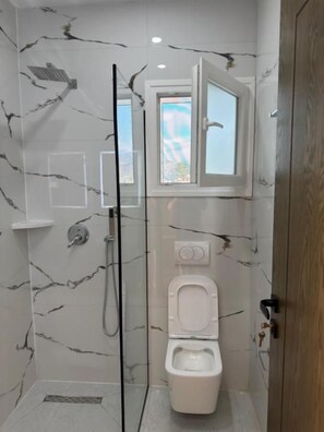 A bathroom with a shower, toilet, and a window. - Petro Rooms and View (Vau-Dejës)
