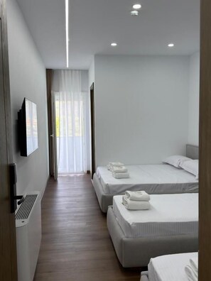 A hotel room with two beds, a flat-screen TV mounted on the wall, and a window with sheer curtains. - Petro Rooms and View (Vau-Dejës)