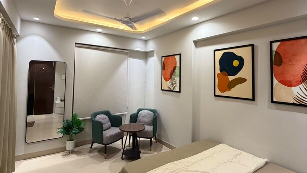 A modern hotel room with a bed, seating area, and artwork on the walls. - Slate VII by Ved Homes (Jaipur)