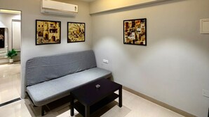 A modern living room with a grey sofa, a black coffee table, and three framed artworks on the wall. - Slate VII by Ved Homes (Jaipur)
