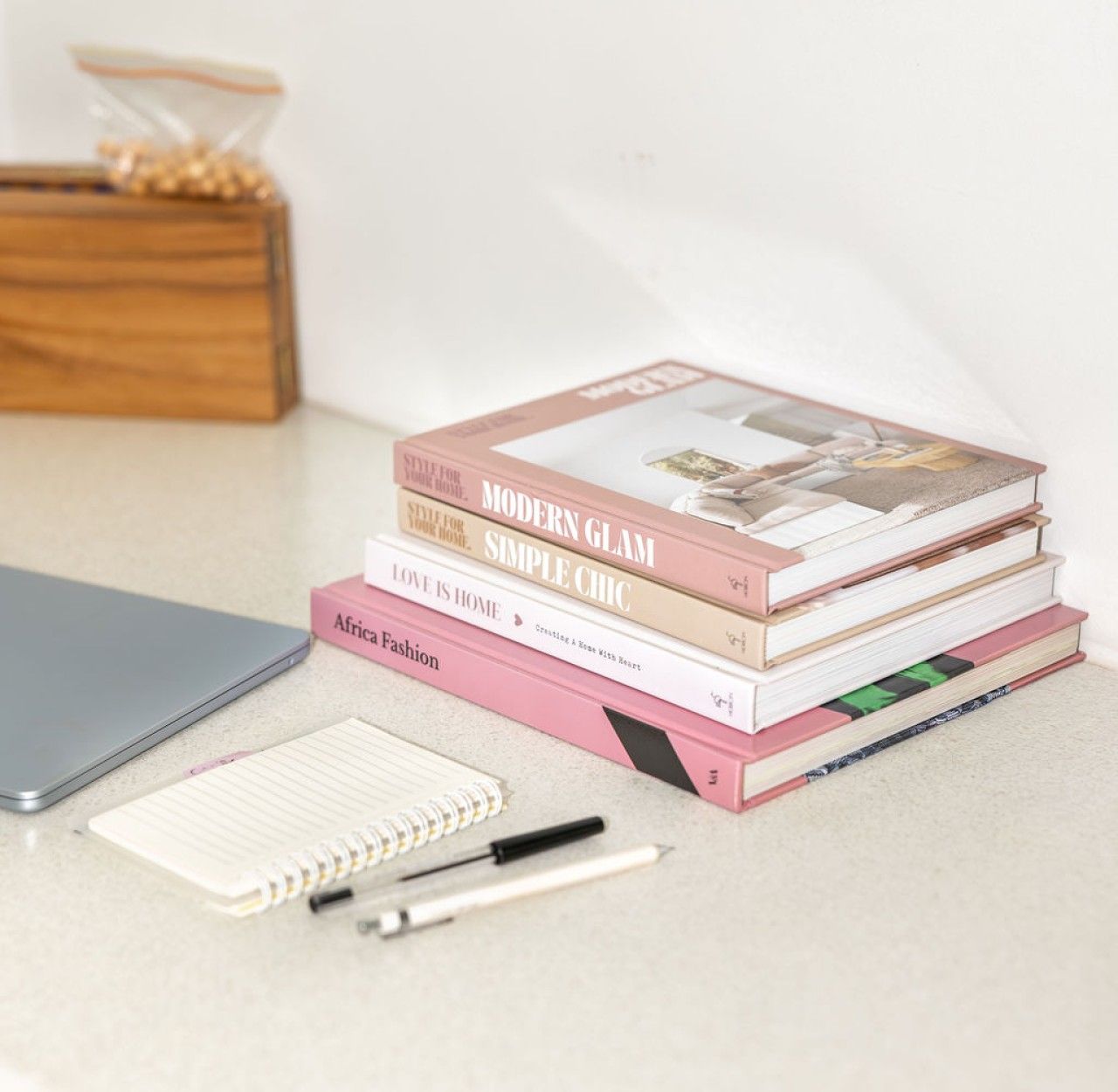 Boeken op een tafel, met een notitieboek, pen en een houten doos op de achtergrond.