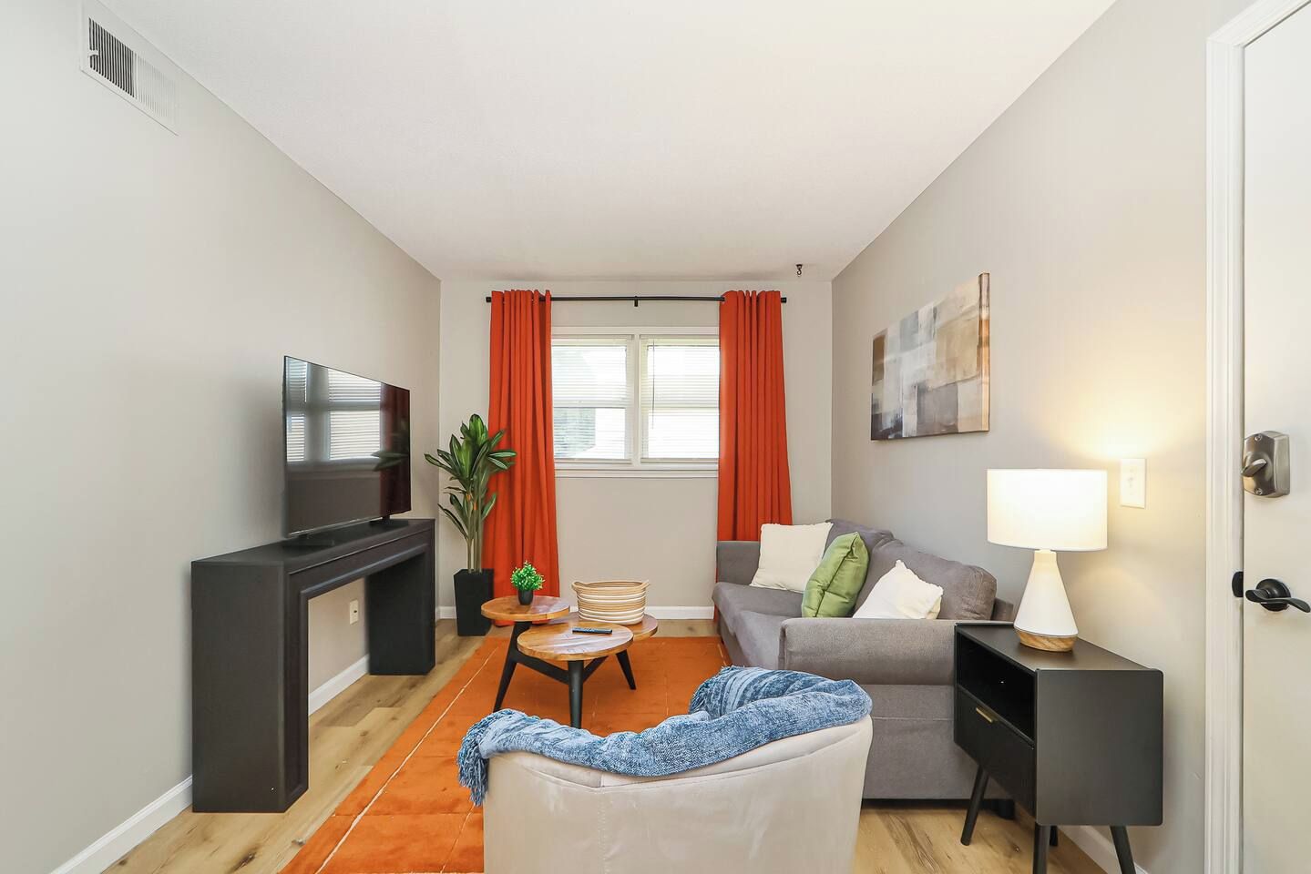 A compact living room with a flat-screen TV, a sofa, a coffee table, and a lamp.