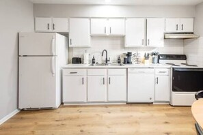 A kitchen with white cabinets, a refrigerator, a stove, and a sink. - Fremont Stylish Stay | Near K-State | Free Parking (Manhattan)