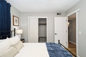 A bedroom with a bed, bedside table, lamp, and a closet with a door leading to another room. - Fremont Stylish Stay | Near K-State | Free Parking (Manhattan)