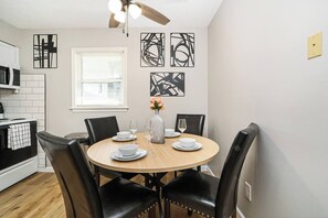 A dining area with a round table, black chairs, and a ceiling fan. - Fremont Stylish Stay | Near K-State | Free Parking (Manhattan)