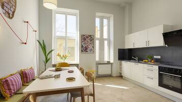 A modern kitchen with white cabinets, a black stove, and a dining area with a white table and chairs.