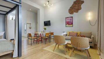 A modern living room with a dining area, a flat-screen TV mounted on the wall, and a brick accent wall.
