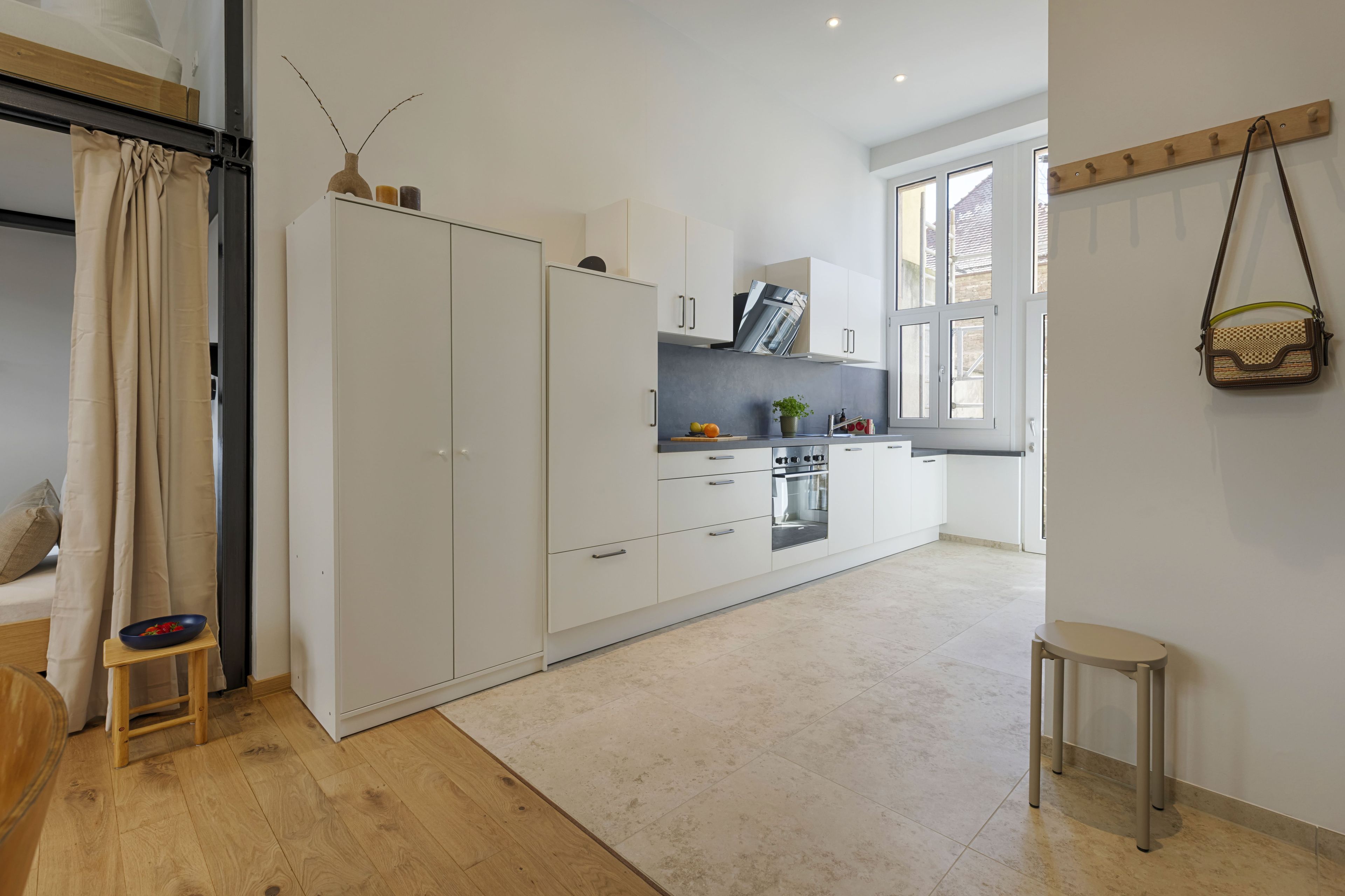 A modern kitchen with white cabinets, a built-in oven, and a window providing natural light.