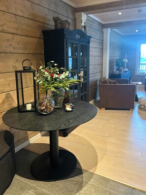 Una mesa redonda con superficie de vidrio, rodeada por un panel de madera y un mueble con puertas de cristal.