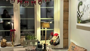 A dining area with a long table set for a meal, decorated with festive garlands and a lit candle centerpiece.