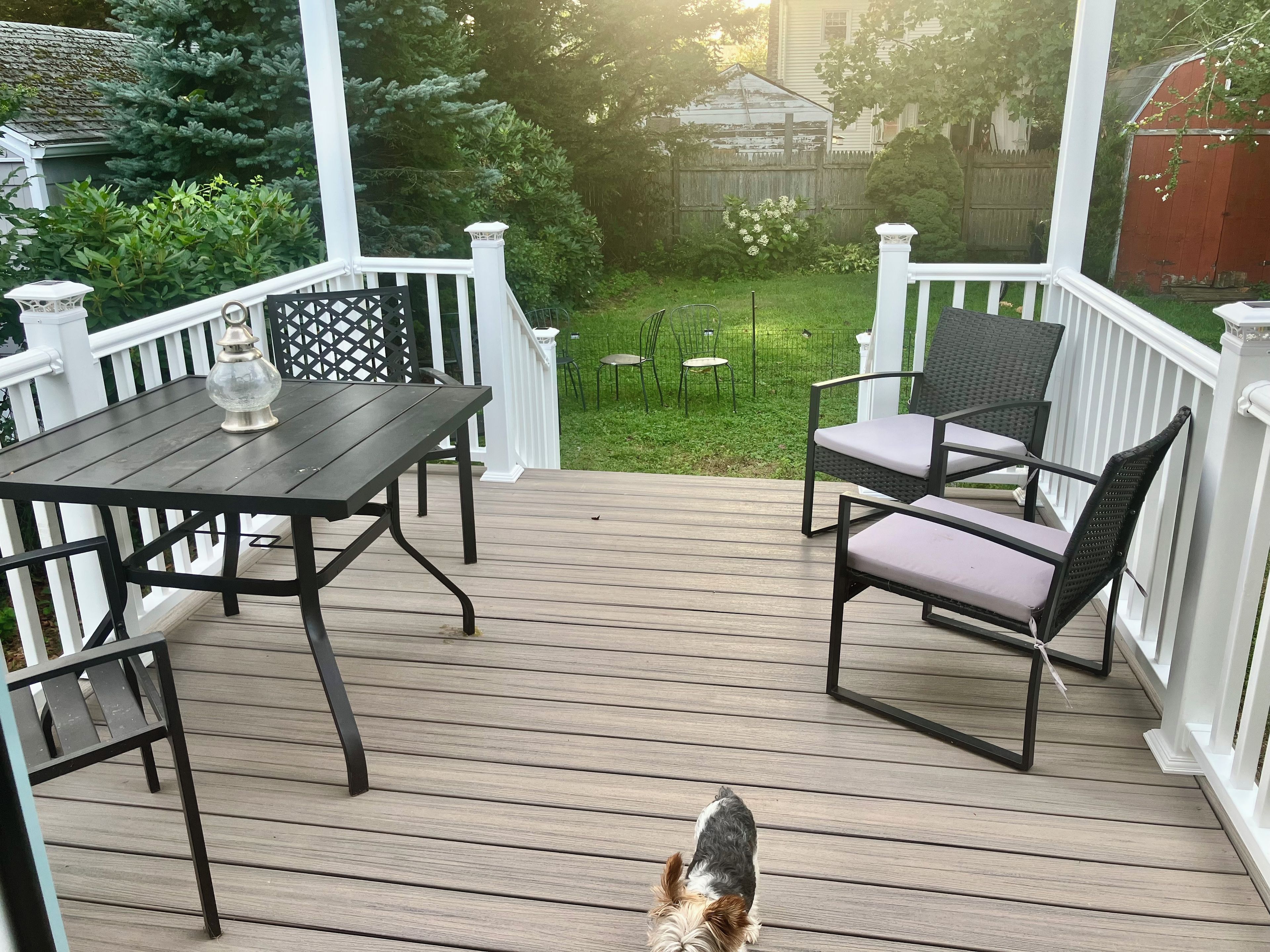 A wooden deck with a table and chairs, surrounded by white railings.