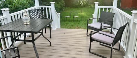 A wooden deck with a table and chairs, surrounded by white railings.