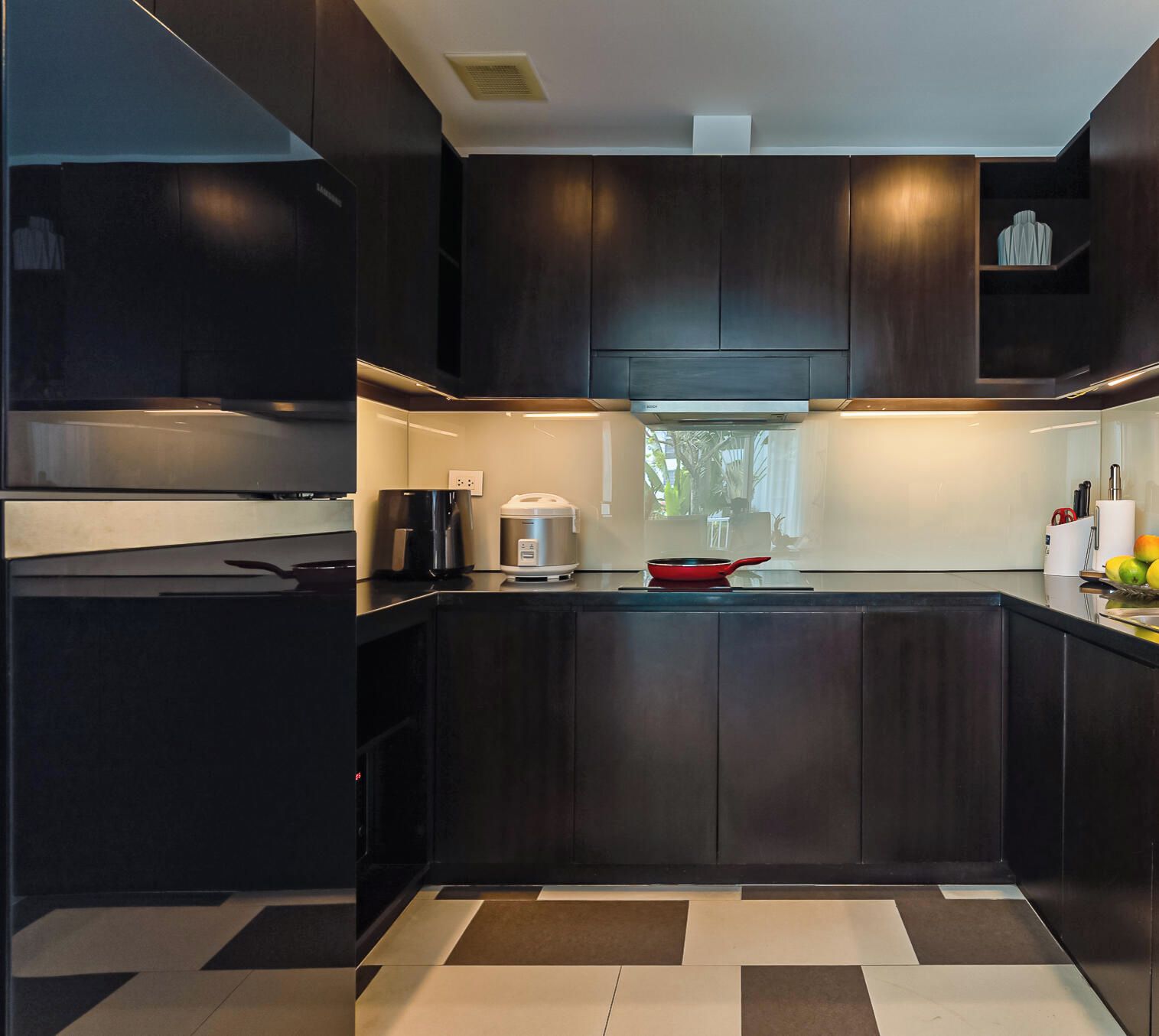 A modern kitchen with dark cabinetry, a central island, and a window providing natural light.