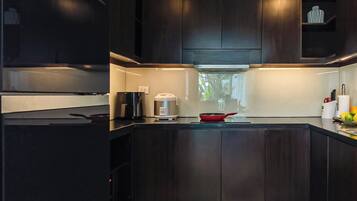 A modern kitchen with dark cabinetry, a central island, and a window providing natural light.