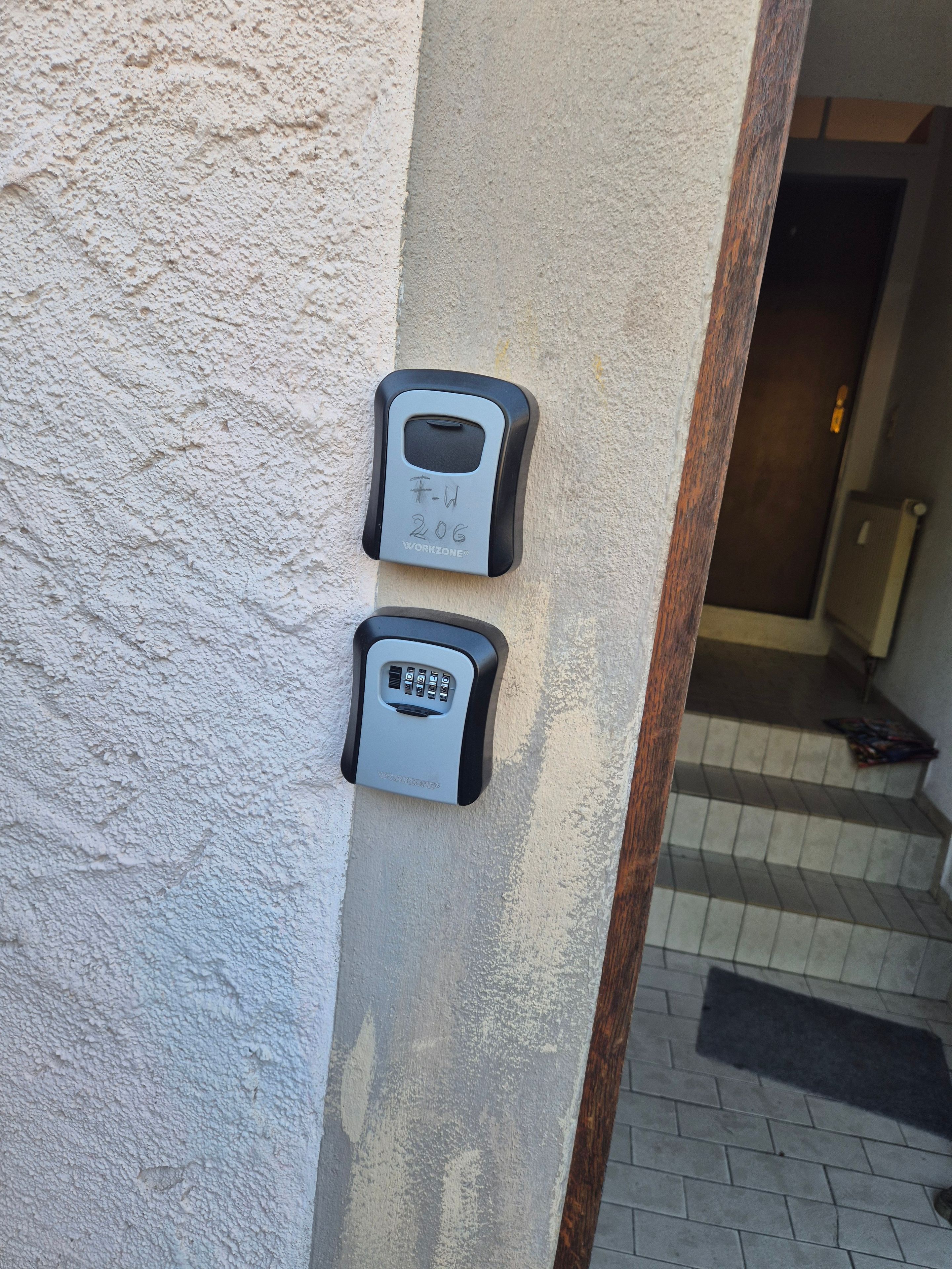 Dos teclados de seguridad montados en una pared con textura, con un marco de madera y una puerta al fondo.