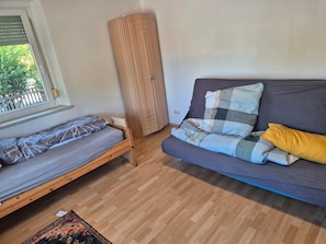 Ett rum med en säng, en soffa, ett fönster och en garderob i trä.