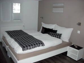 A bedroom with a bed, bedside tables, and a window with blinds. - Bergfreude Kuonen Appartement/Fewo 4-Bettwohnung by Interhome (Saas-Grund)