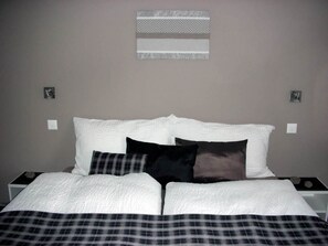 A bed with white bedding and a plaid blanket, two bedside tables, and a wall-mounted light fixture. - Bergfreude Kuonen Appartement/Fewo 4-Bettwohnung by Interhome (Saas-Grund)