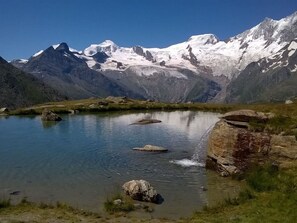 Un lago di montagna con acque cristalline, circondato da cime innevate e rive rocciose.