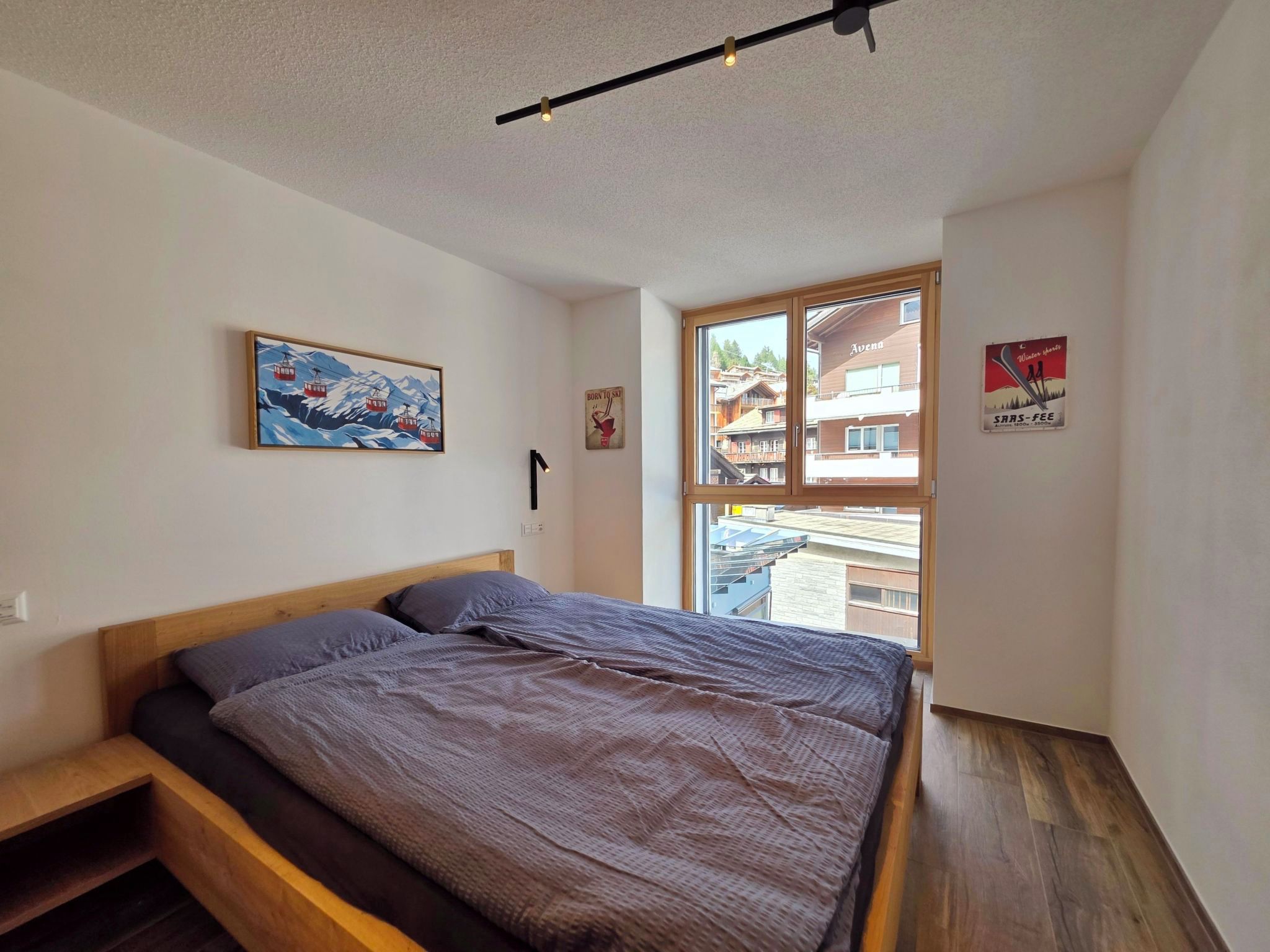 A bedroom with a bed, a window, and a view of buildings outside.