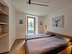 Ein Schlafzimmer mit einem Bett, einem Fenster und einer Tür, die auf einen Balkon führt.