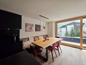 A modern dining area with a wooden table and red chairs, a black cabinet, and artwork on the wall. - Du Glacier A3 Appartement/Fewo Appartement/Fewo by Interhome (Saas-Fee)