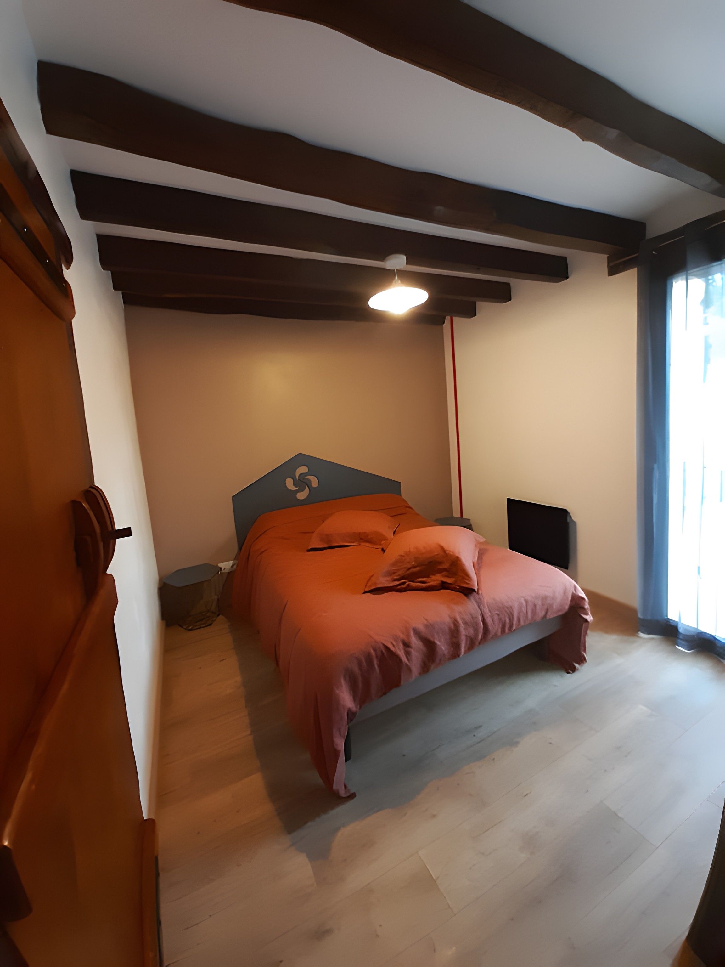 Una camera da letto con un letto, un comodino, un altoparlante e una finestra con tende.