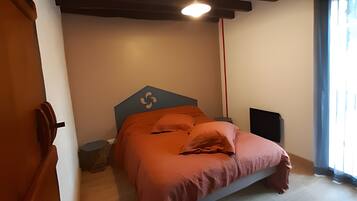 Una camera da letto con un letto, un comodino, un altoparlante e una finestra con tende.