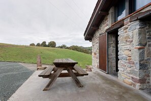 A stone building with a wooden picnic table in front.