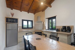 Una cocina moderna con techo de madera, un refrigerador, un microondas, una estufa y una cafetera.
