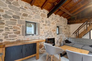 Un interior rústico con paredes de piedra, techo de madera, un sofá, una mesa y una escalera.