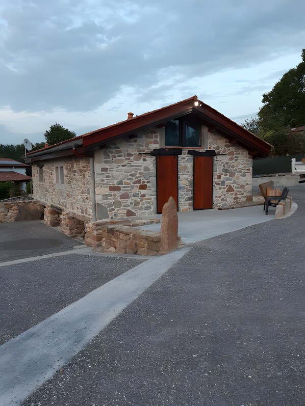 A stone building with a red roof and a single entrance door.
