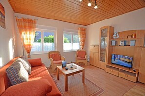 A cozy living room with a sofa, chairs, a coffee table, and a television. - Right on the Baltic Sea beach! Just 20 meters to the beach, patio, sleeps up to 4 people (Glowe)