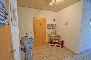 A hallway with a wooden door, a model ship on a shelf, a fire extinguisher, and a pressure gauge. - Right on the Baltic Sea beach! Just 20 meters from the beach, patio, sleeps up to 4, pets allowed (Glowe)
