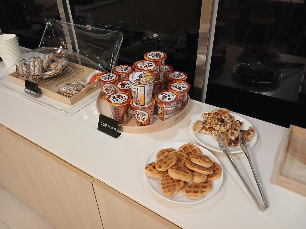 Een buffet met verschillende etenswaren, zoals verpakte snacks, bekers en wafels.