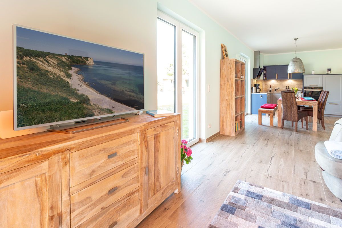 Una cocina moderna con un televisor de pantalla plana grande, armarios de madera y un comedor con mesa y sillas.