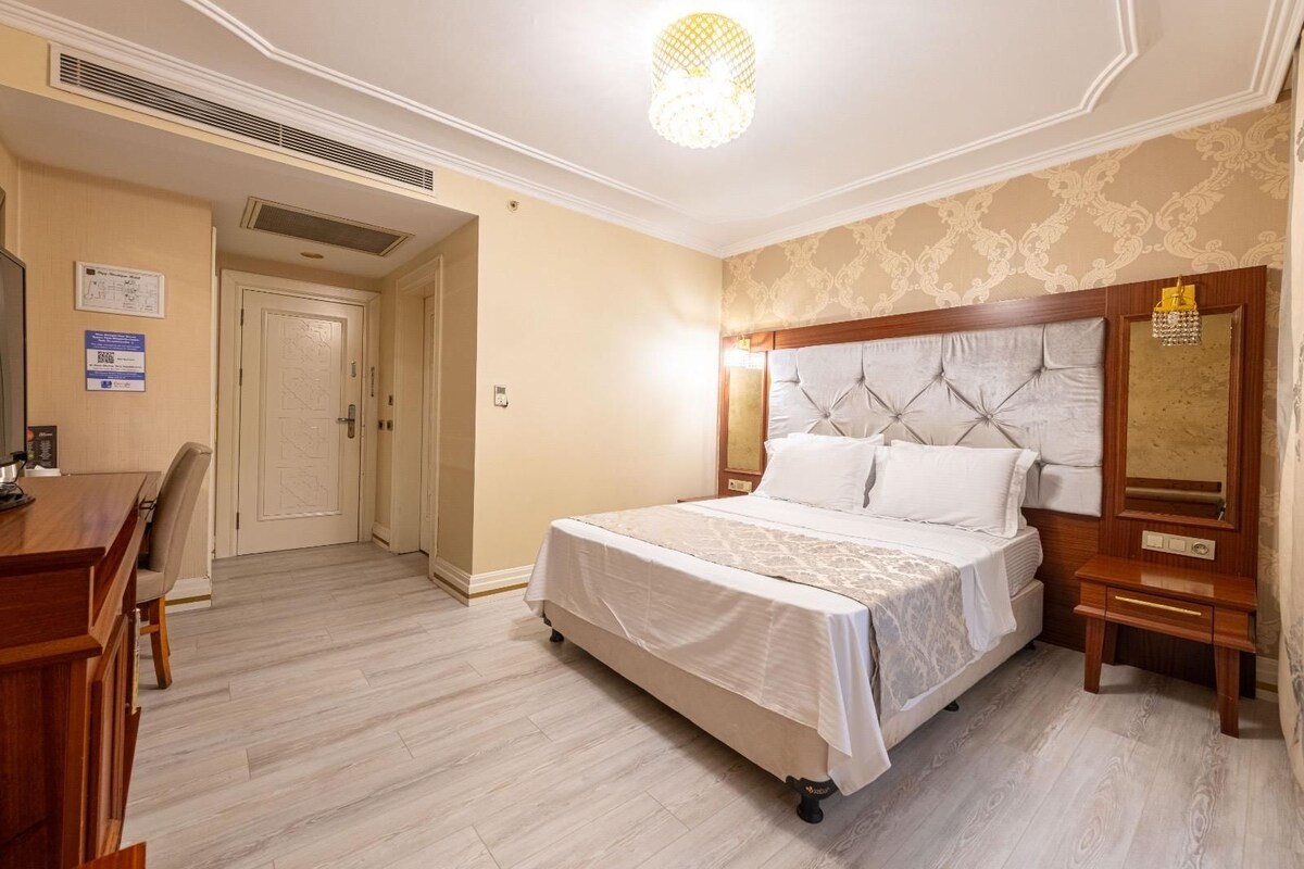 A hotel room with a bed, bedside table, and a desk with a chair.