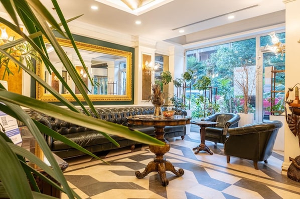 A hotel lobby with a black leather sofa, a wooden coffee table, and a large mirror.