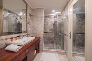 A modern bathroom with a marble shower enclosure, a double sink vanity, and a large mirror.