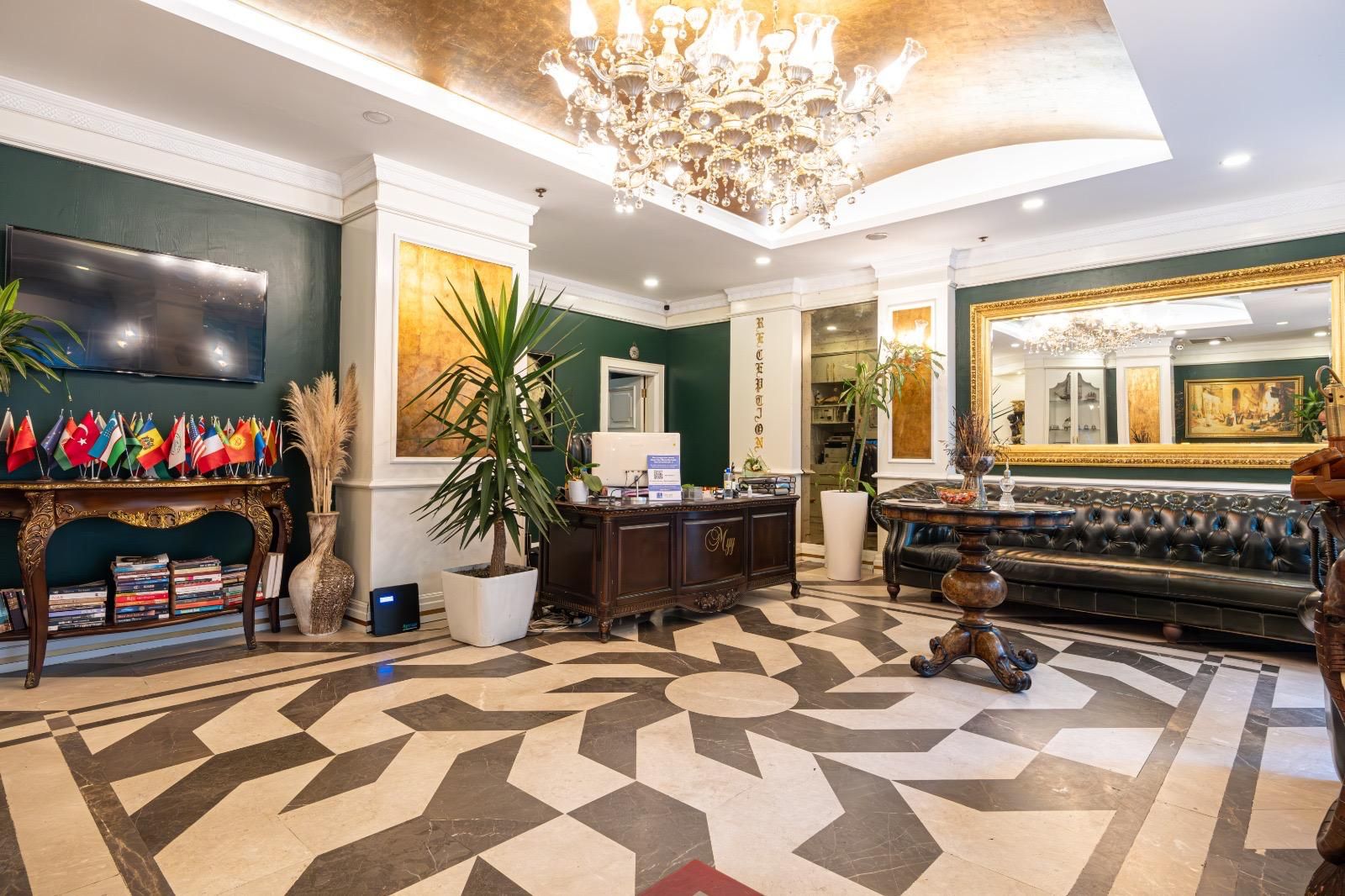 Eine Lobby mit Schachbrettmuster-Boden, einer Rezeption, einer Couch und einem Chandelier.