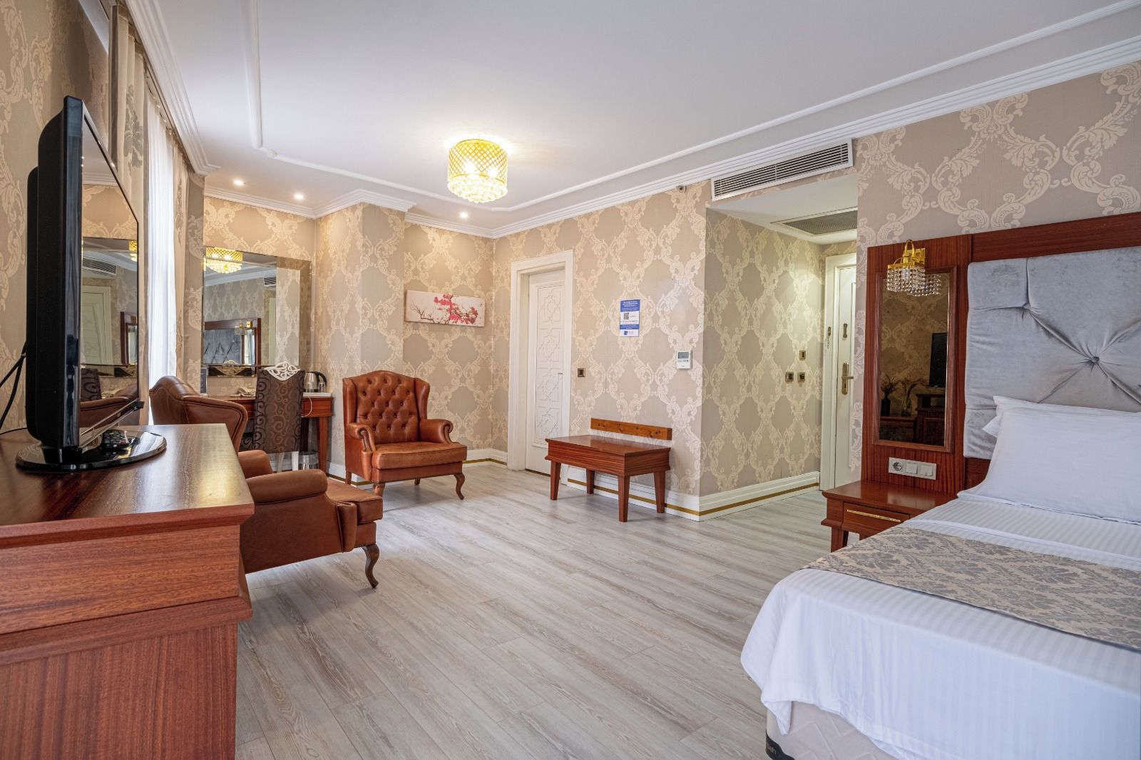Una habitación de hotel con una cama, un escritorio, una silla, un televisor y un espejo grande.