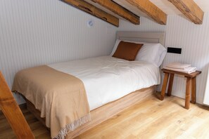 A single bed with a headboard, a bedside table with a lamp, and a wooden floor. - La Casita Azul | Seaside House in Malpica, Costa da Morte (Malpica)