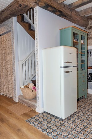 A kitchen with a white refrigerator, a teal cabinet, and a patterned floor. - La Casita Azul | Seaside House in Malpica, Costa da Morte (Malpica)