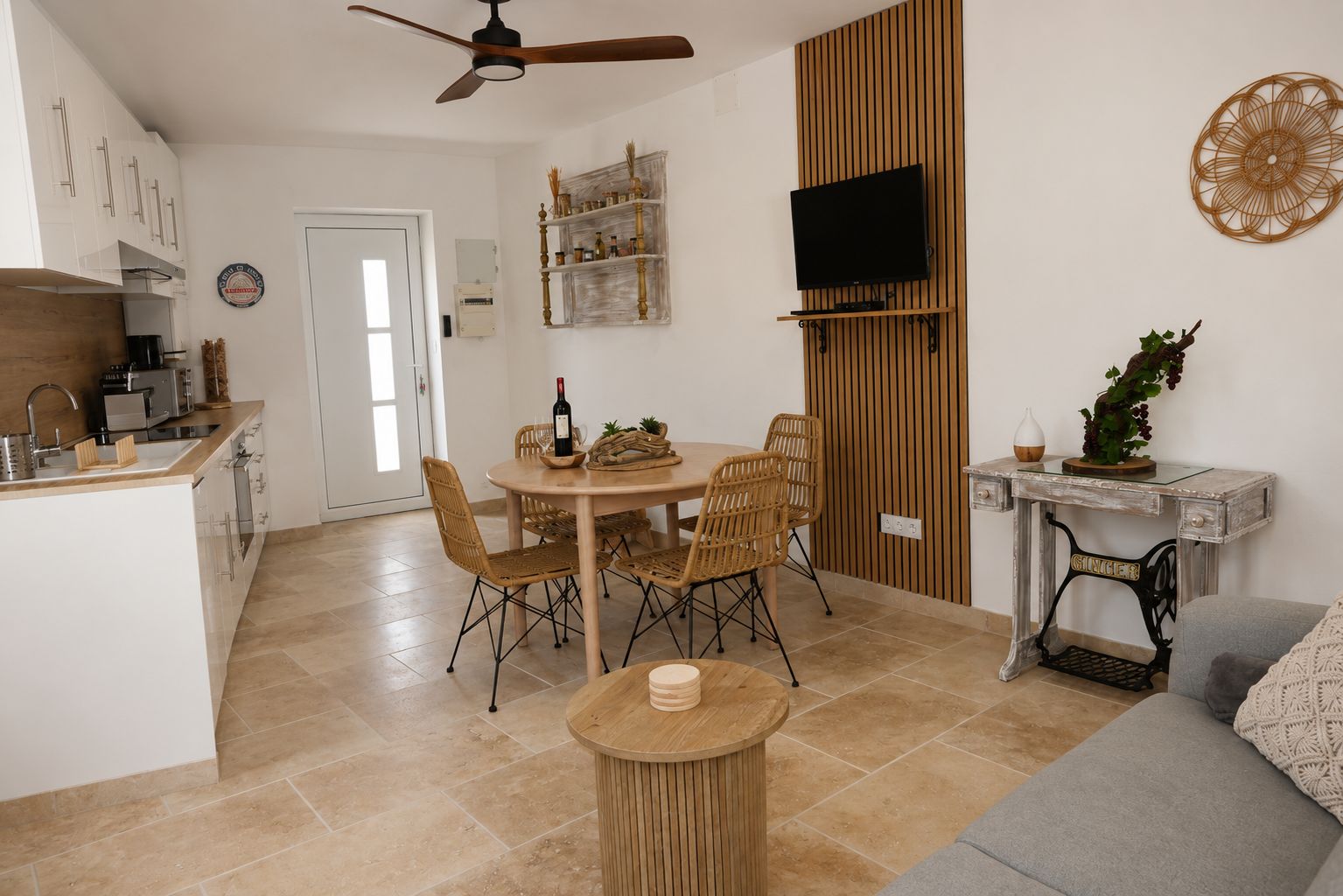 A modern kitchen with a dining area, a television mounted on a wooden panel, and a vintage sewing machine.
