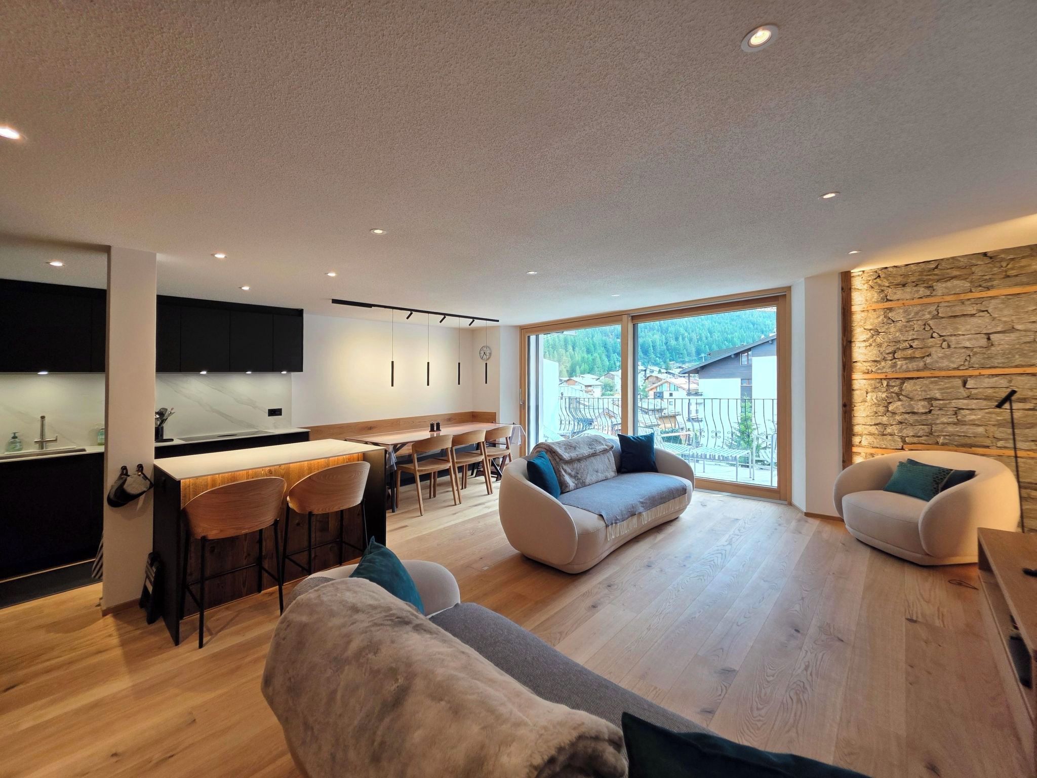A modern interior with a kitchen, dining area, and seating space with a view.