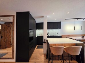 A modern kitchen with a central island, black cabinetry, and wooden accents. - Du Glacier B3 Appartement/Fewo Appartement/Fewo by Interhome (Saas-Fee)