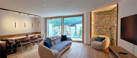 Ein modernes Wohnzimmer mit einer Couch, einem Essbereich und einer Wand mit Steinverkleidung.