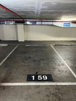 Eine Parkgarage mit Betonböden und -wänden, gekennzeichneten Parkfeldern sowie Hinweisschildern für reservierte und Hotelparkplätze.